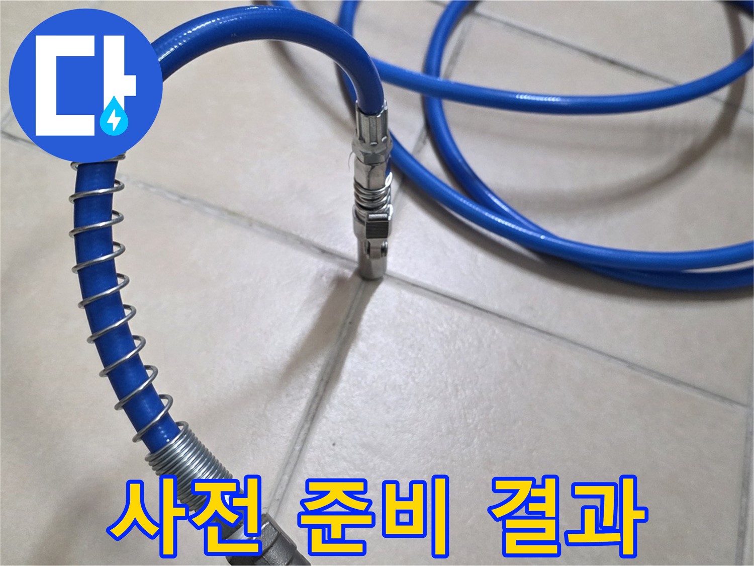 타일 바닥에 길게 놓인 파란색 배관용 호스