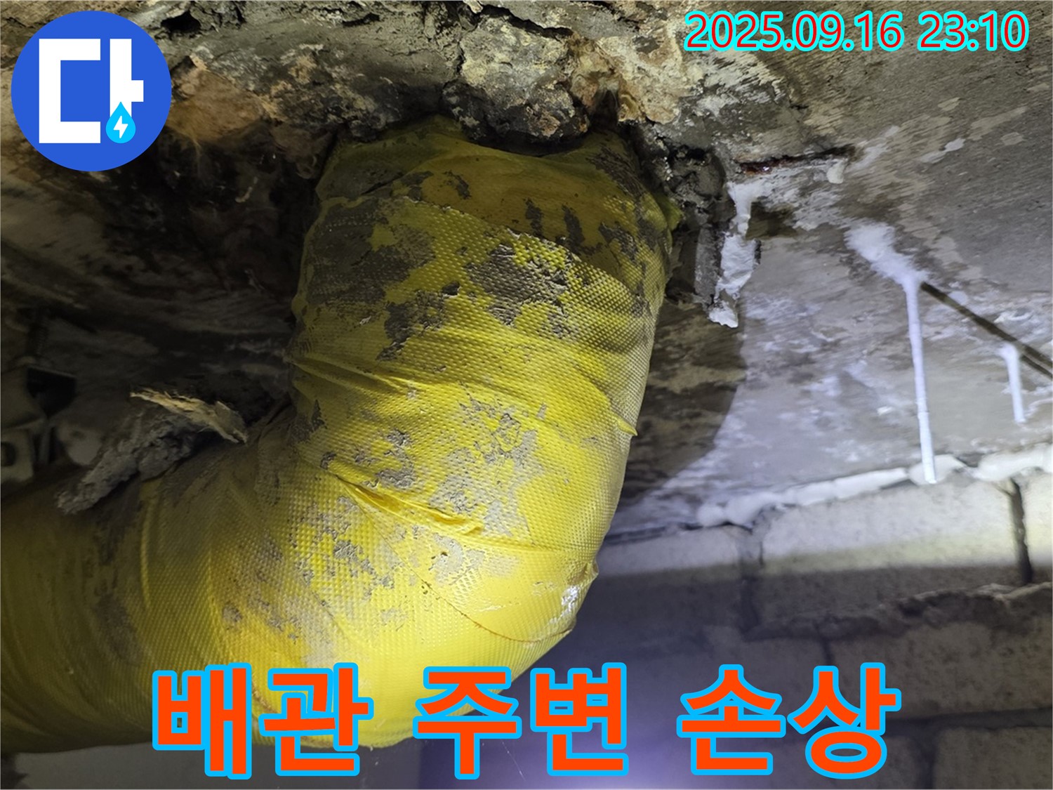 노란 배관 주변 콘크리트가 누수로 인해 심하게 손상된 모습 - 건물 안전에 심각한 영향을 줄 수 있습니다.