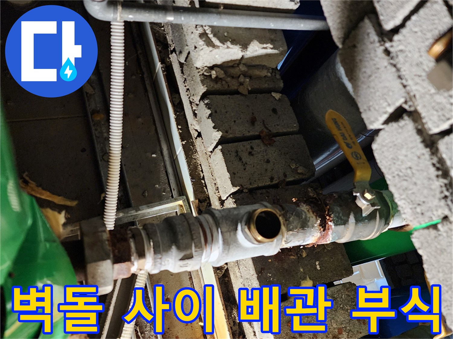 벽돌 틈새에 위치한 노후된 금속관과 밸브의 모습