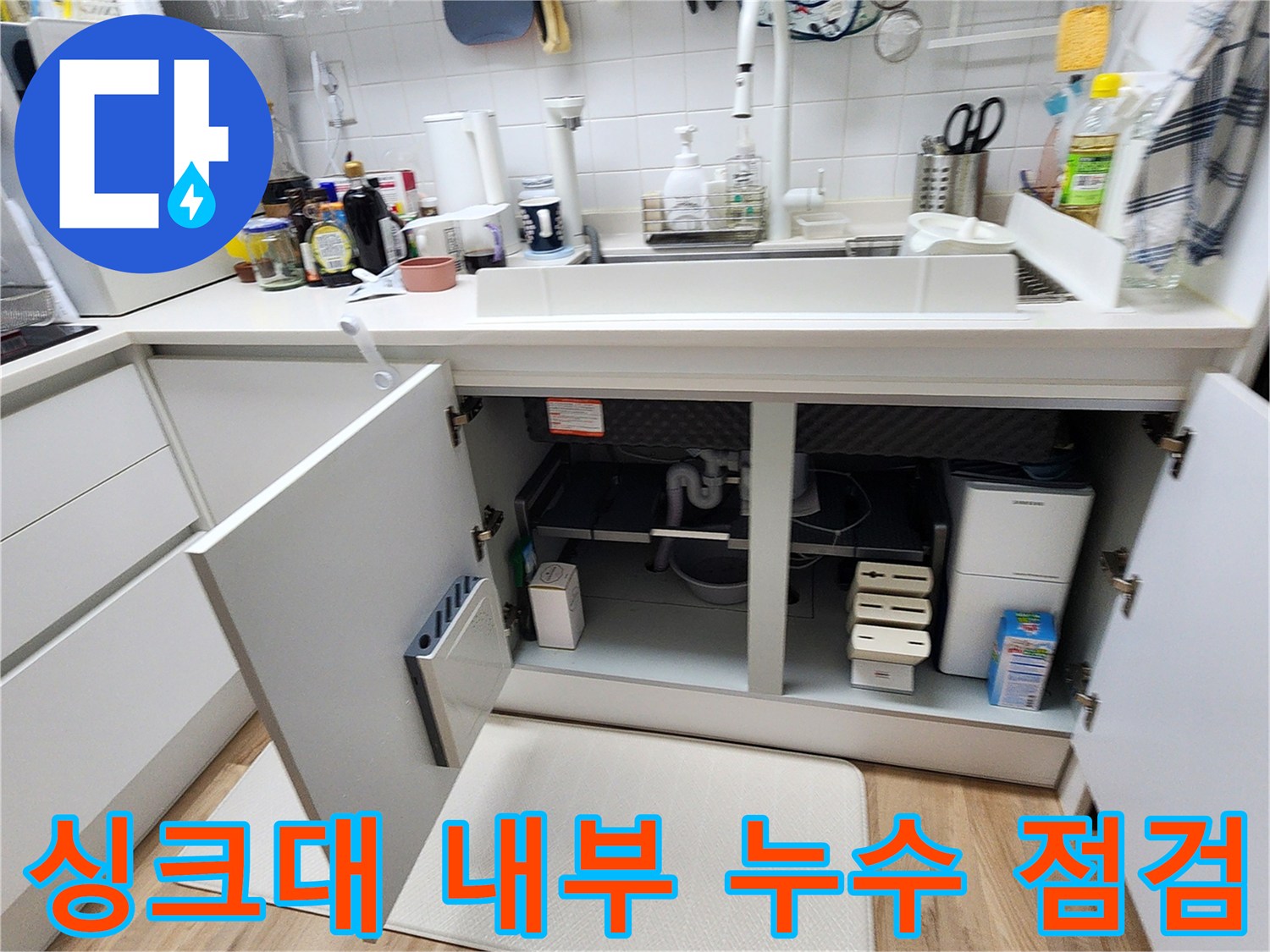 싱크대 아래쪽 배관 부위를 확인하기 위해 하부장을 열어놓은 사진입니다.