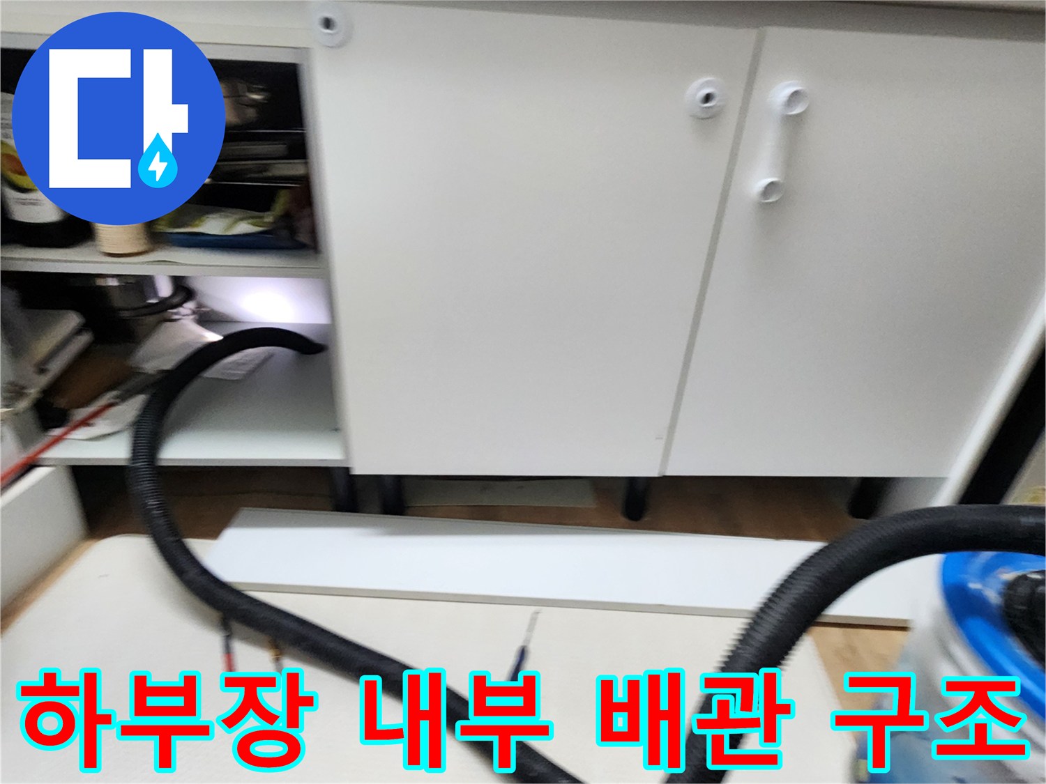 싱크대 아래쪽 배관 호스와 주변 바닥 공간의 모습입니다.