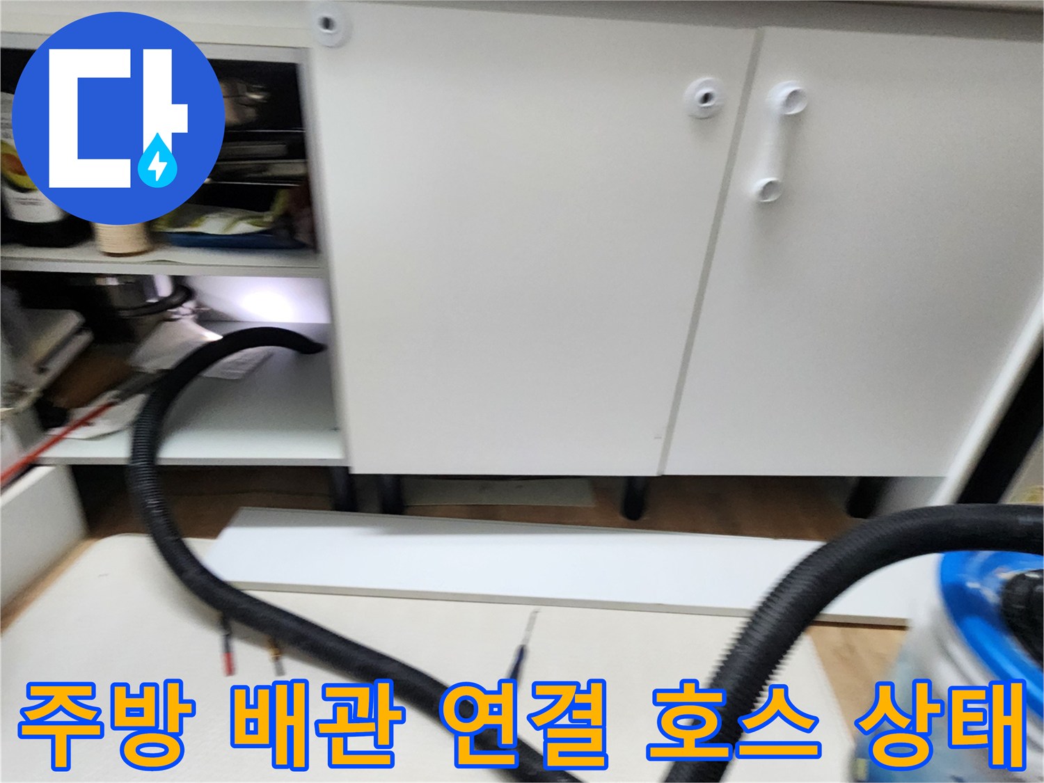 싱크대 아래쪽으로 뻗어 있는 검은색 배관 호스 이미지입니다.