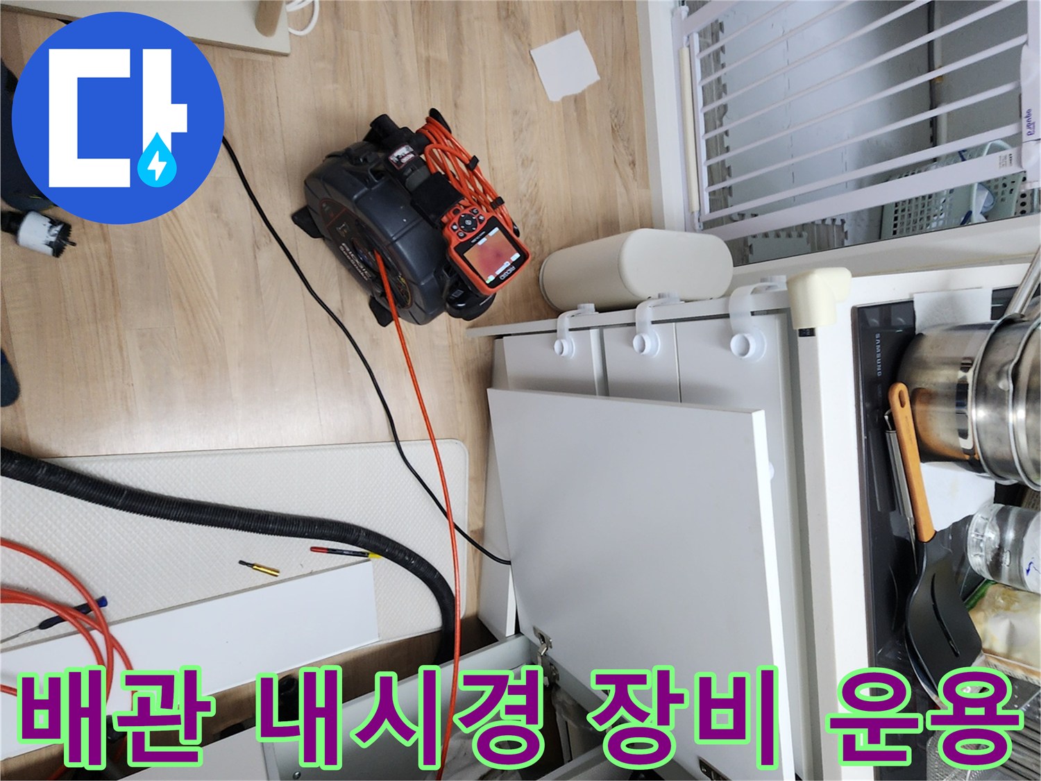 싱크대 하단 공간에 배치된 배관 검사용 내시경 카메라와 케이블입니다.
