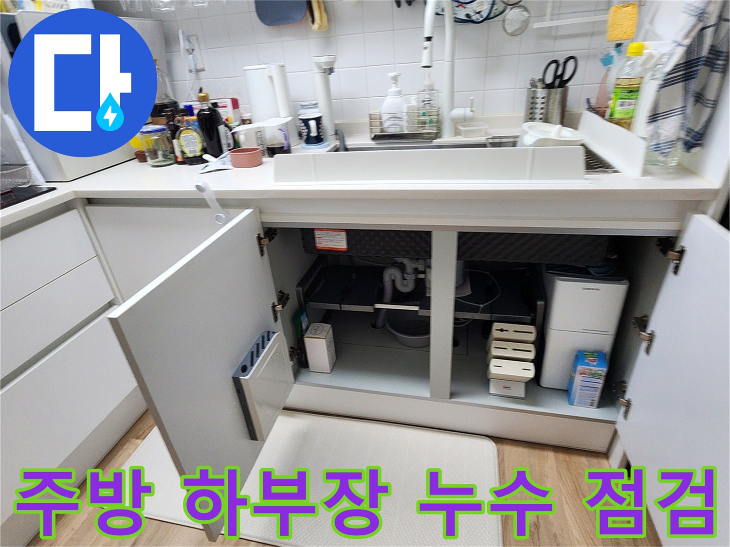열려 있는 싱크대 하부장 내부와 배관 연결 부위 근접 촬영