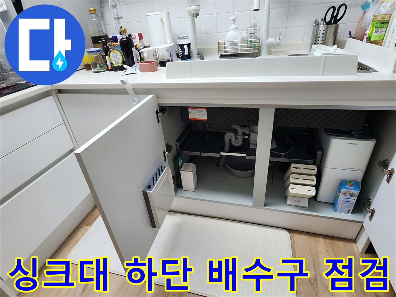 열려있는 싱크대 하부장 안쪽의 배수관 및 분배기 노출 상태