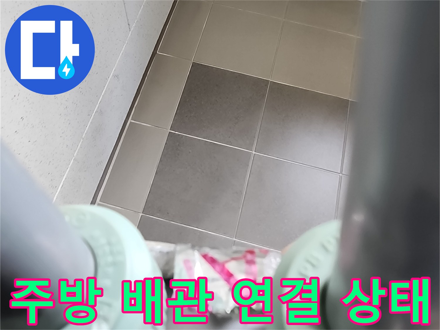타일 바닥과 싱크대 하부 배관의 근접 모습