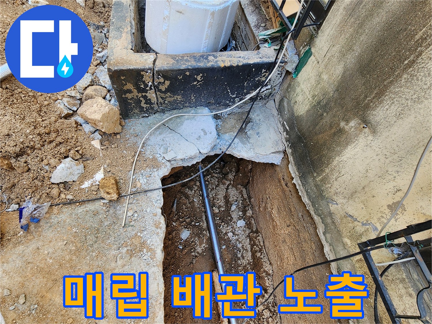외벽 하단부-콘크리트 층 아래에 노출된 누수 배관 상태