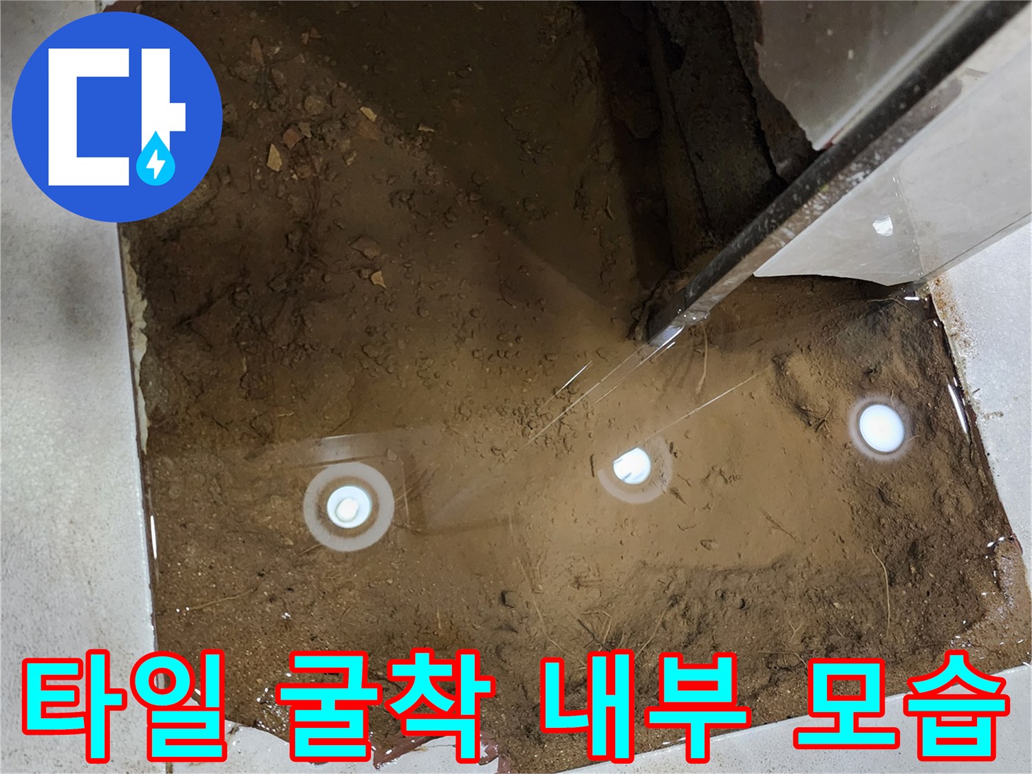 바닥 타일 제거 후 보이는 누수 흔적과 젖은 토사