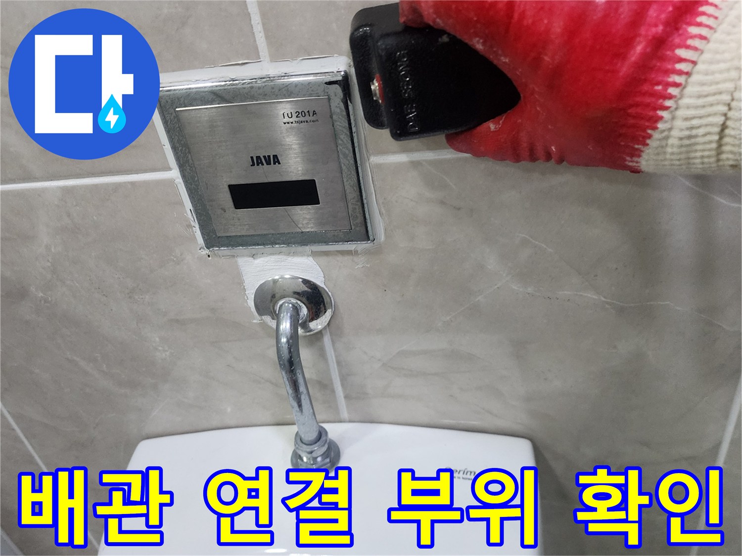 소변기 상단 자동 밸브와 급수 배관의 연결 상태를 점검하는 장면입니다