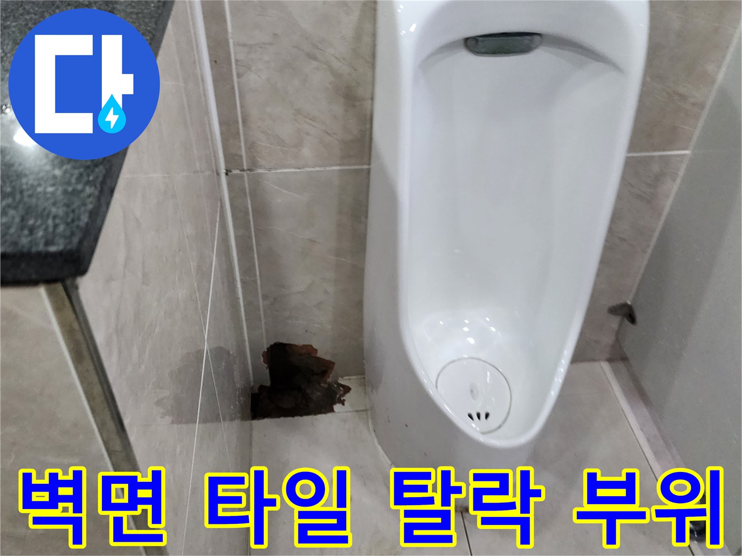 화장실 소변기 옆-파손된 타일과 노출된 내부 구조물