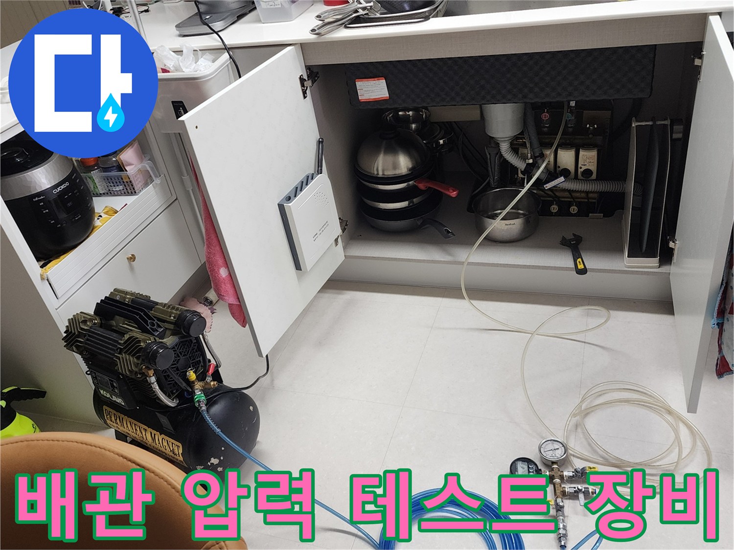 주방 싱크대 하부장-누수 탐지를 위해 설치된 공압 콤프레샤와 호스