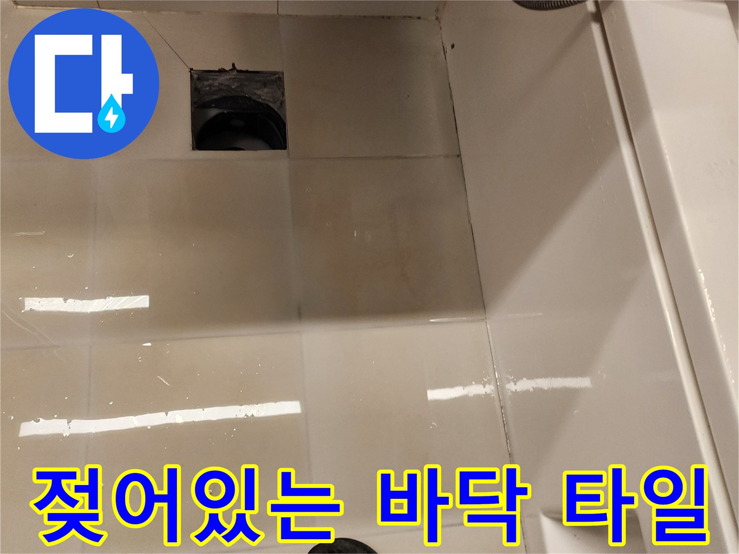 세면대 아래 배수구 주변의 젖은 타일 표면