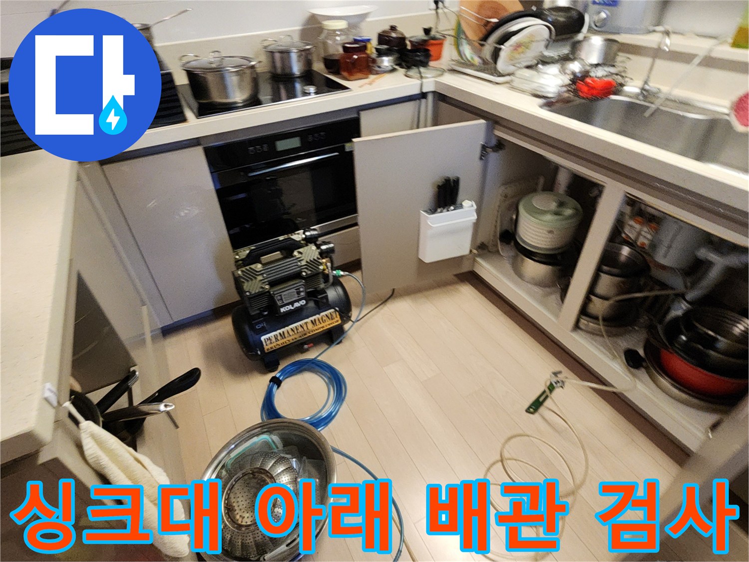 주방 바닥에 놓인 공압 테스트 장비와 파란색 에어 호스 라인
