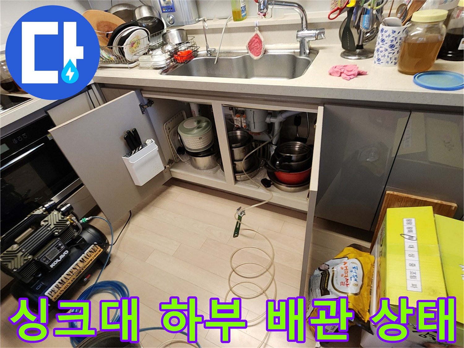 주방 싱크대 아래쪽-노출된 배관과 점검 장비 모습