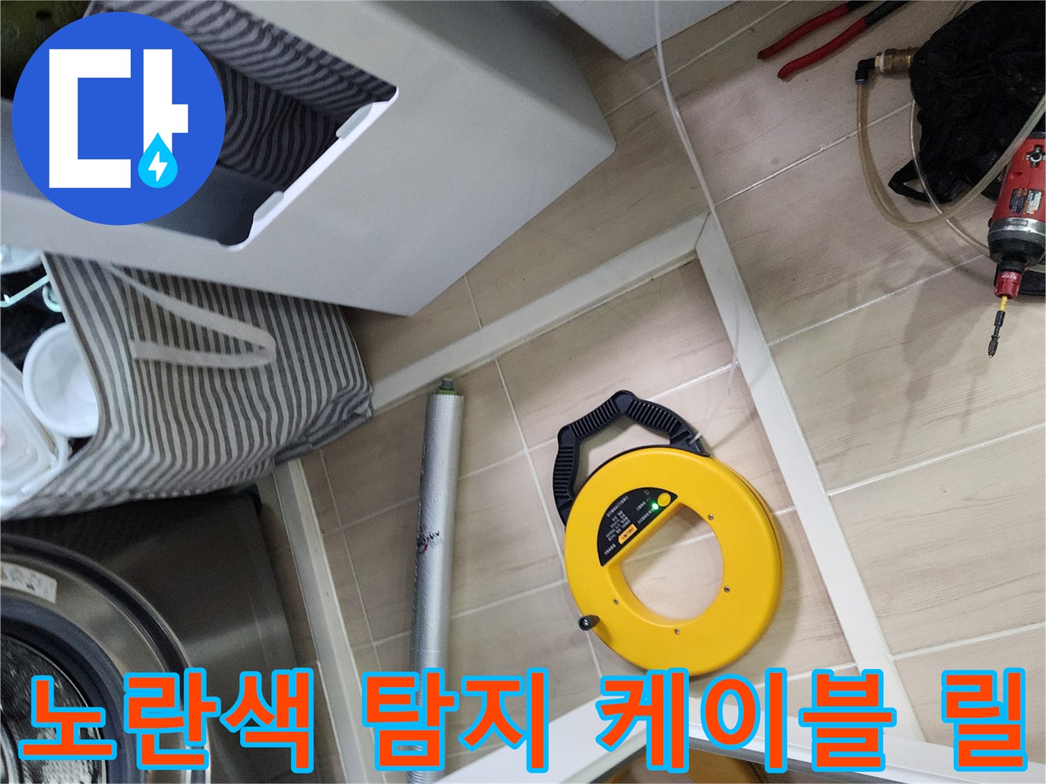 바닥 타일 위에 놓여 있는 노란색 배관 탐지 장비