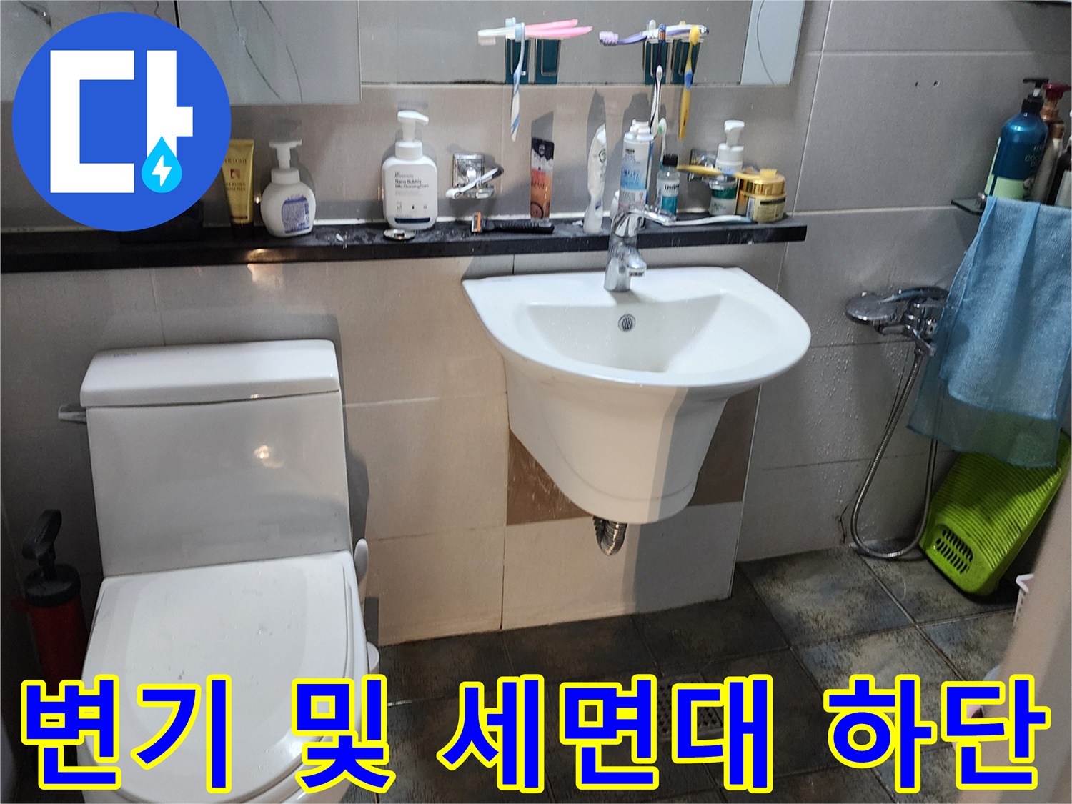 세면대와 변기가 설치된 화장실의 타일 벽면 사진