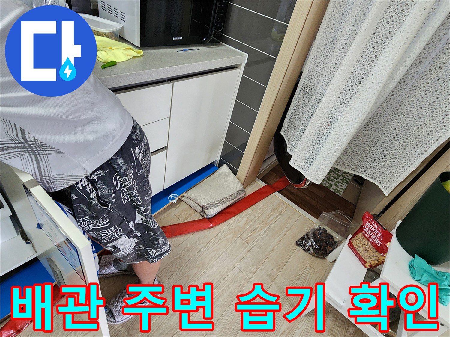 싱크대 하단 배관 근처 바닥의 물샘 징후를 점검하는 사진입니다.