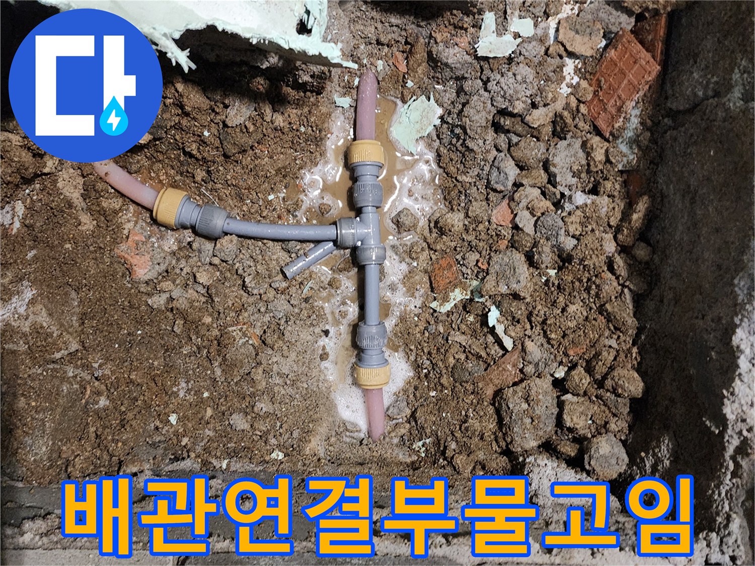 T자형 분기 배관 주위의 젖은 흙과 물샘 흔적