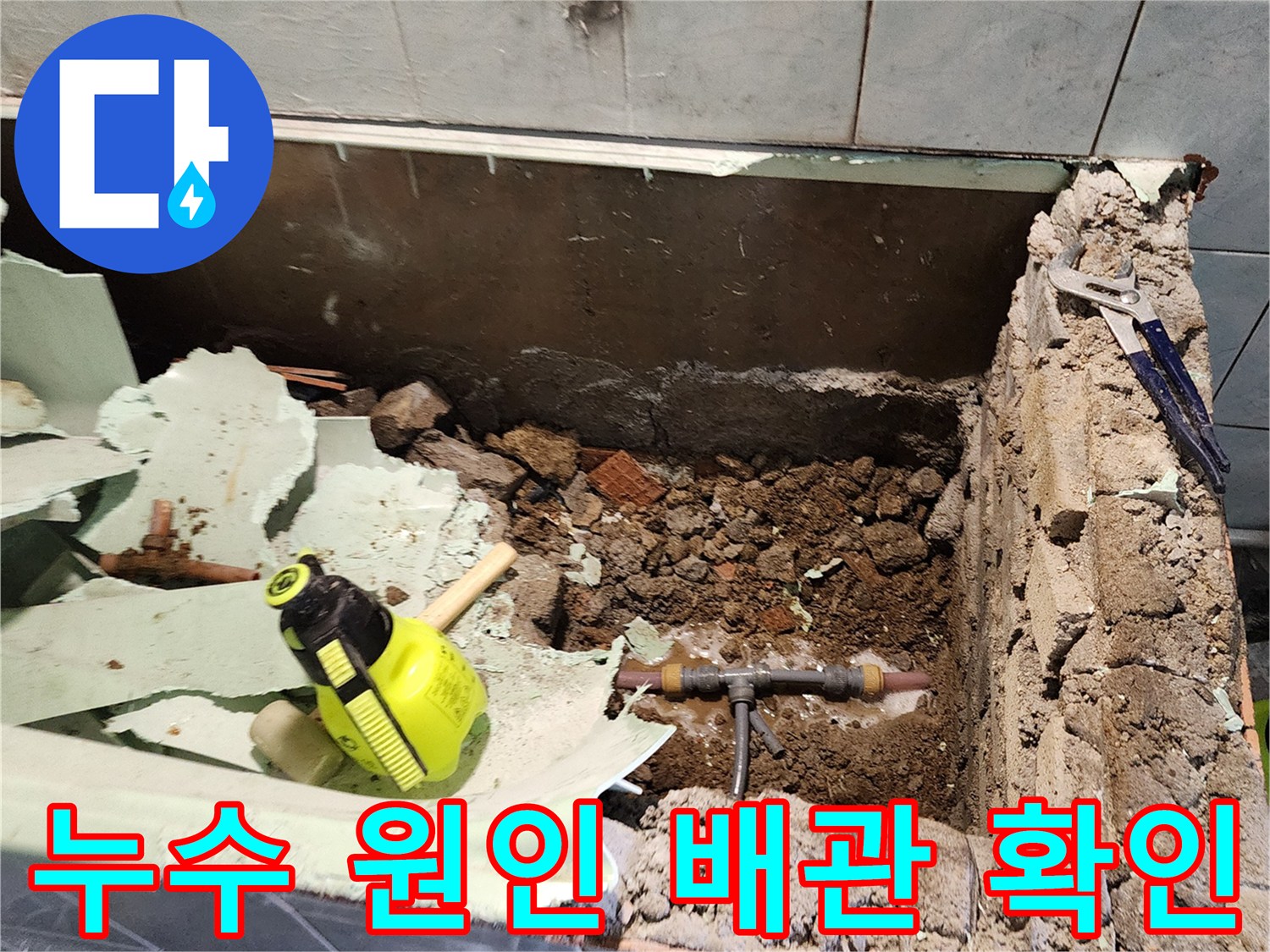 타일 제거 후 드러난 젖은 흙과 T자형 배관 부위