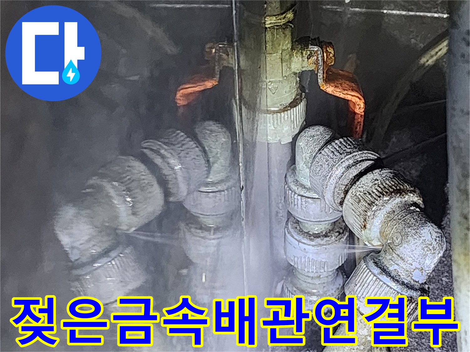 물기가 맺혀 있는 금속 재질의 배관 연결 부위 사진입니다.