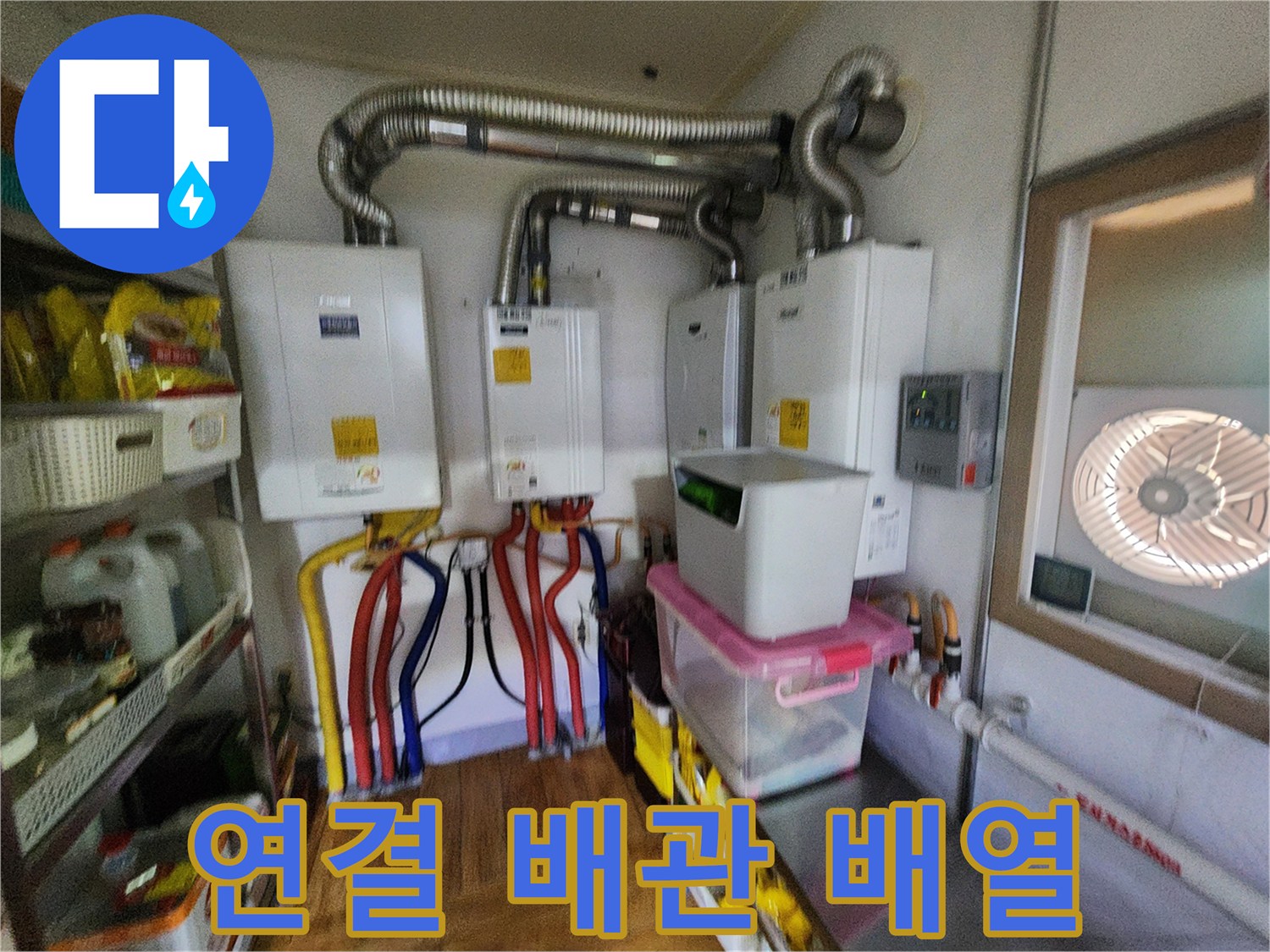 보일러 하단에 복잡하게 연결된 유색 배관들과 은색 연통 모습