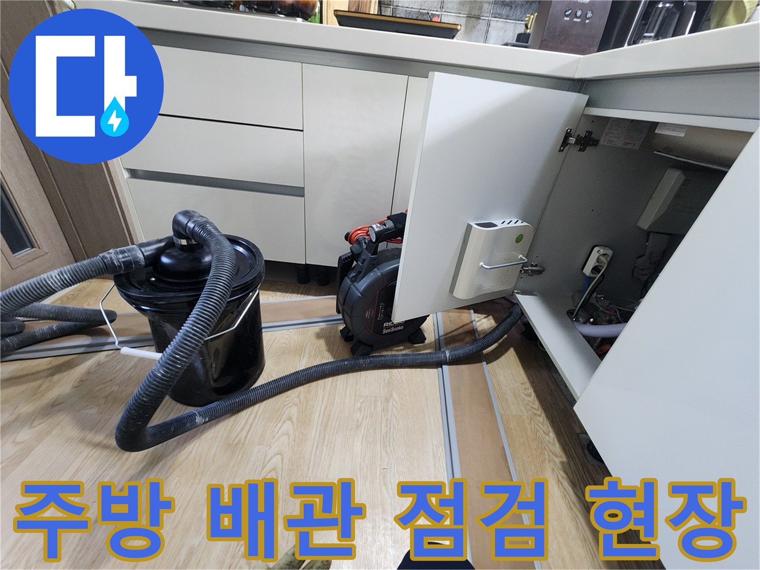 싱크대 하부의 배수 호스와 진단용 장비가 놓여 있습니다.