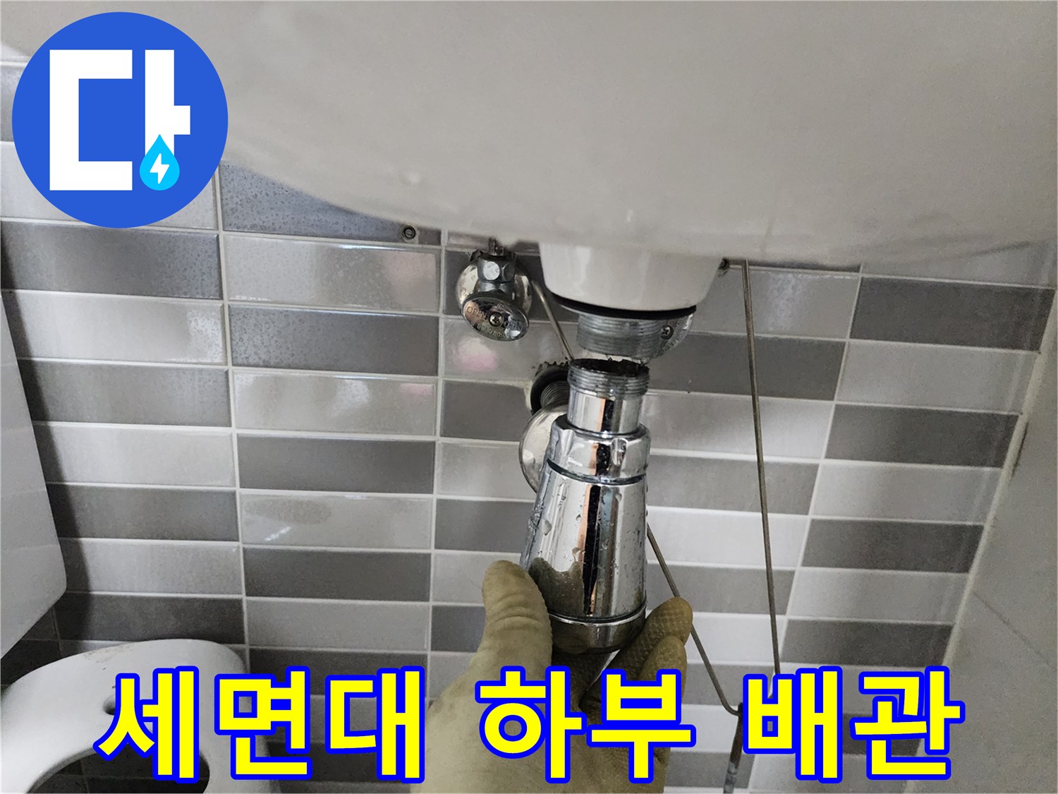 엔지니어가 장갑을 낀 손으로 세면대 아래 크롬 도금된 배수구를 만지고 있습니다.