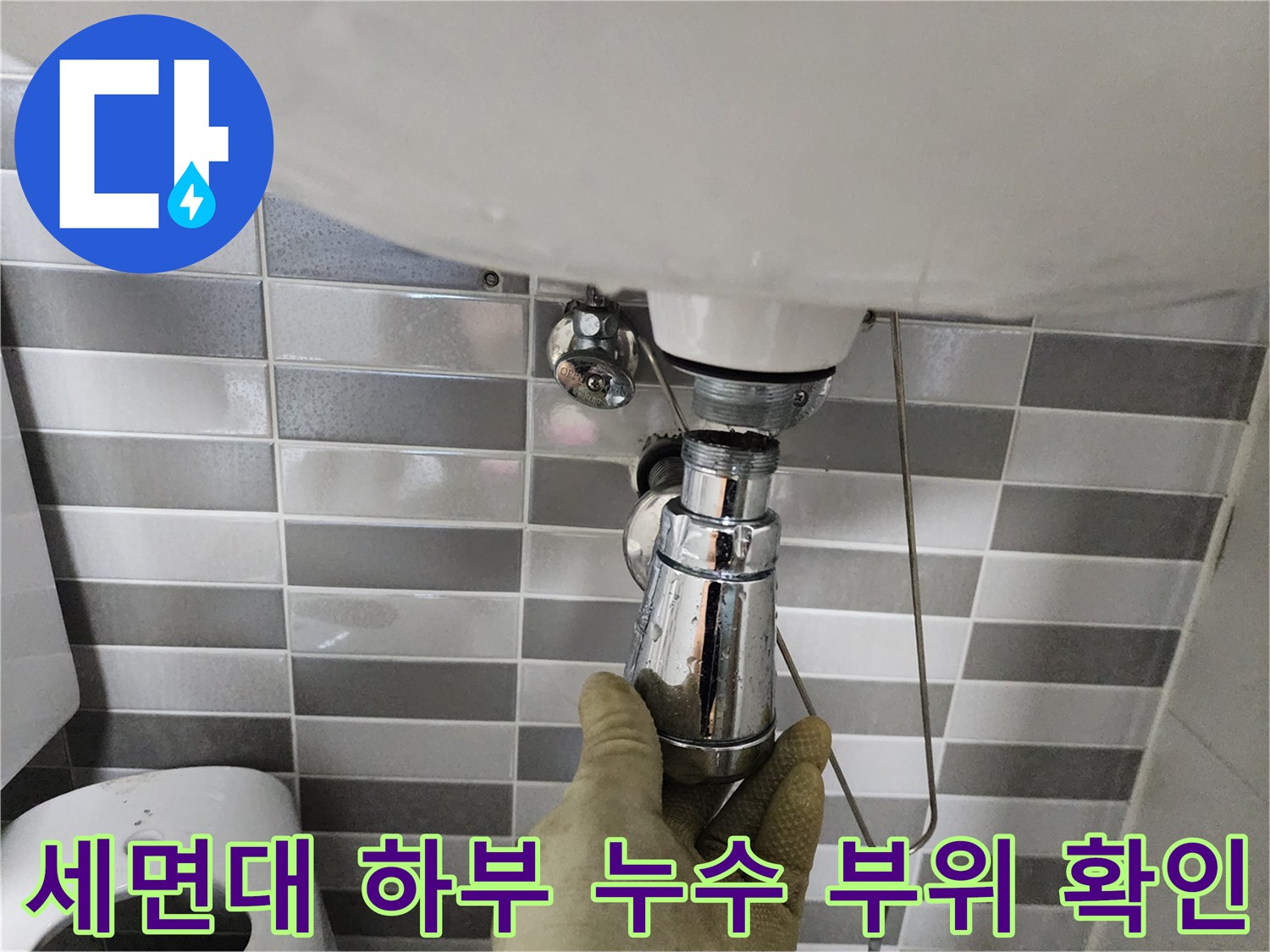 장갑을 착용한 작업자가 세면대 배관 연결 상태를 만져보는 모습