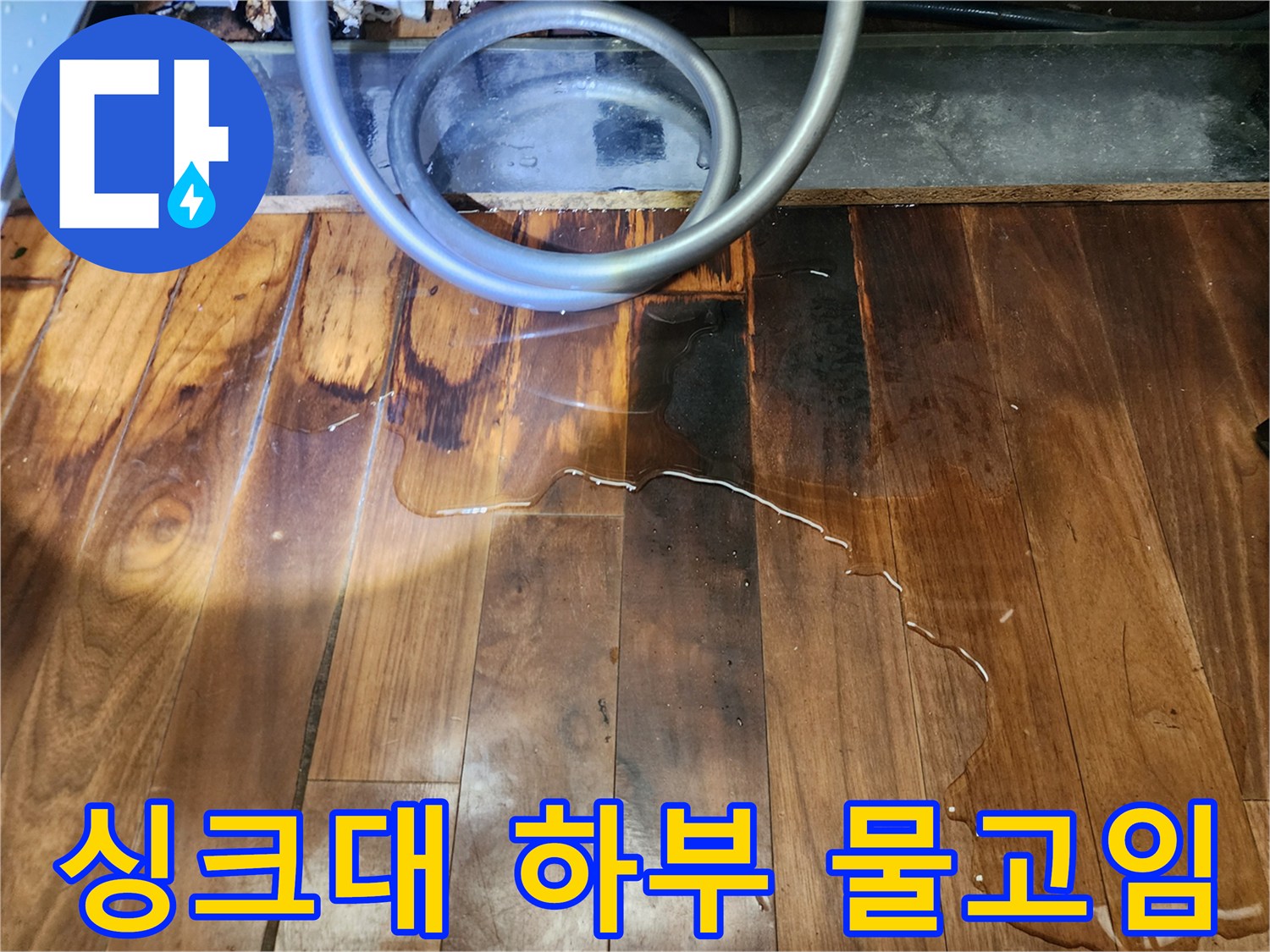 물에 젖어 변색된 마루-싱크대 배관 주변의 습한 바닥 상태
