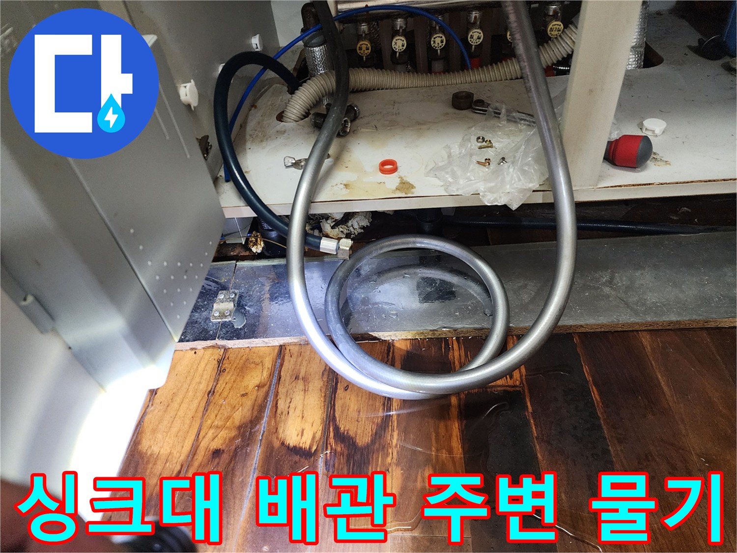 싱크대 배관 연결부 주변에 고여 있는 물과 젖은 마루