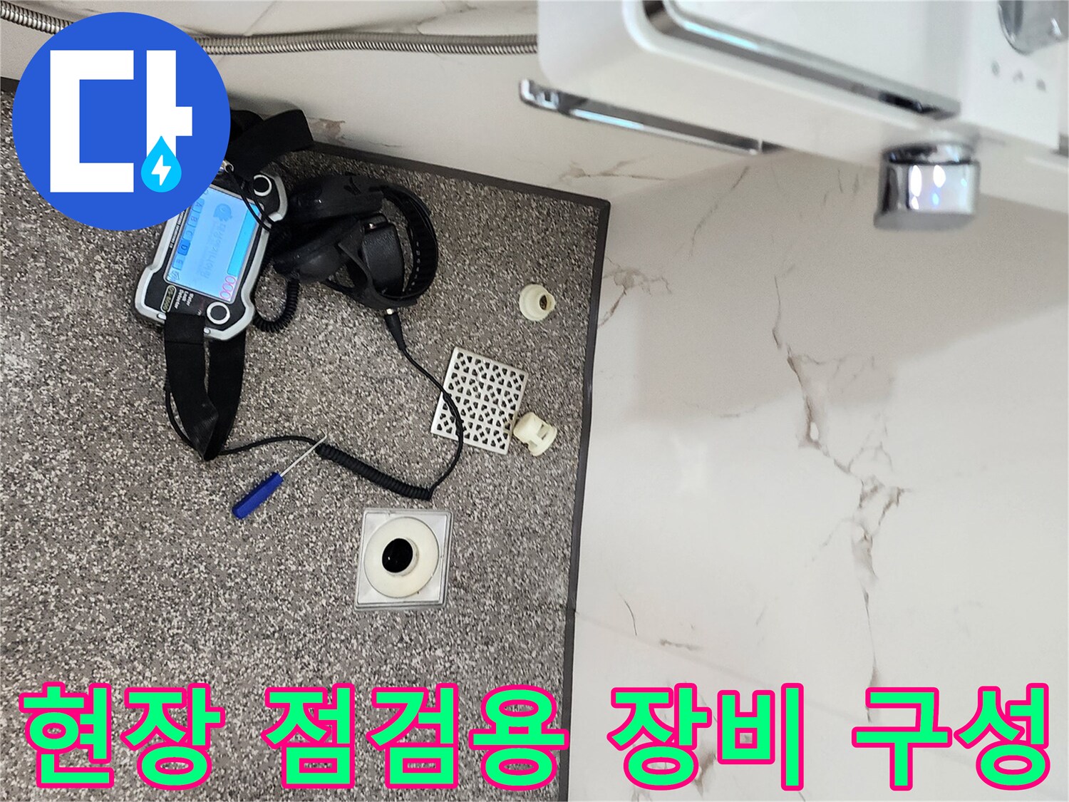 바닥 배수구 옆에 놓여 있는 가스 탐지기와 보조 도구들입니다.