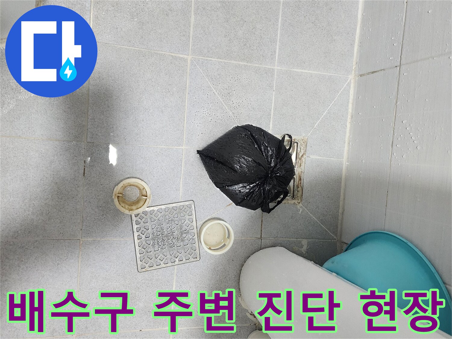 화장실 타일 바닥에 놓인 배수구 부품과 검은 봉투의 작업 모습