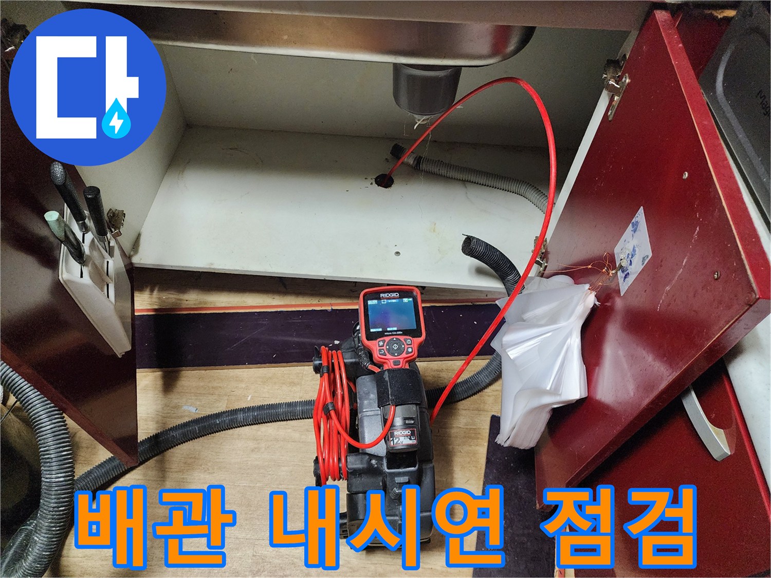 싱크대 하부 배관 상태를 확인하기 위해 내시경 카메라를 투입하는 모습입니다.
