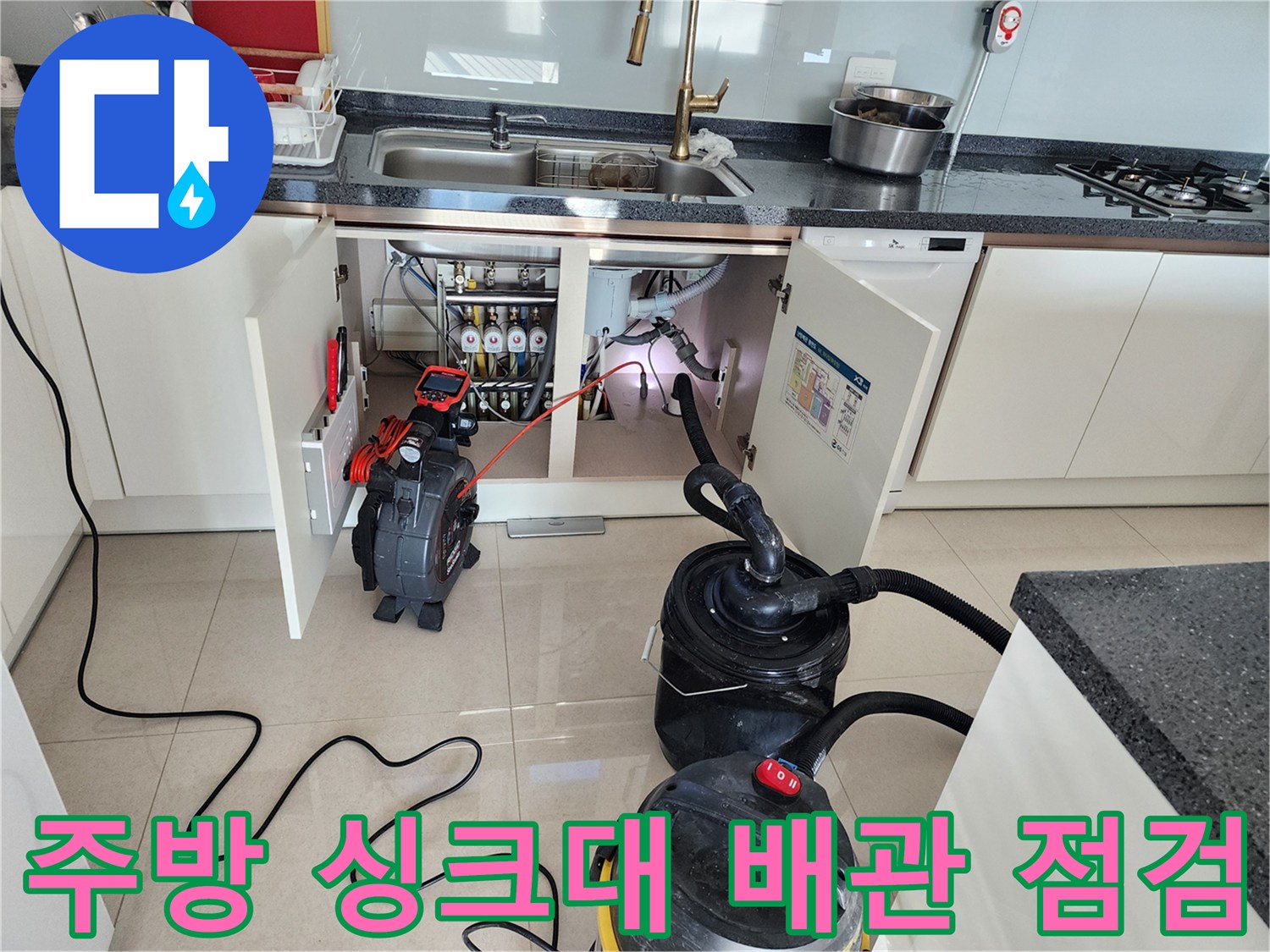 주방 싱크대 하부장 아래에 놓인 전문 배관 내시경 장비와 석션기