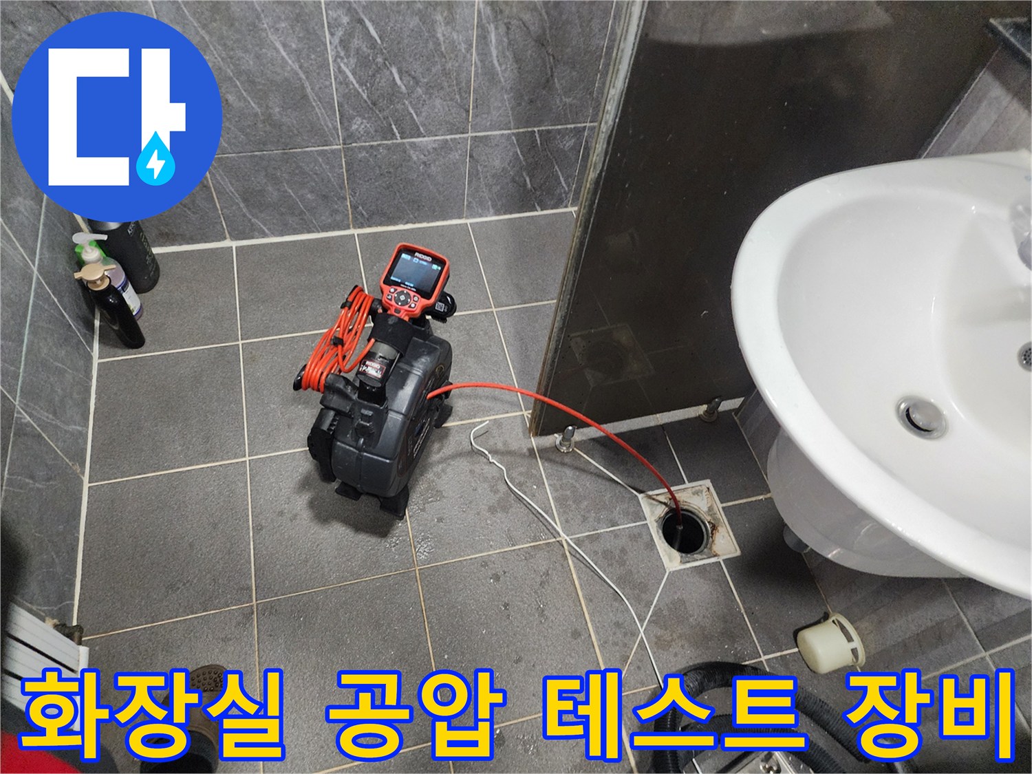 화장실 바닥 타일 위에서 진행 중인 배관 압력 측정 장비