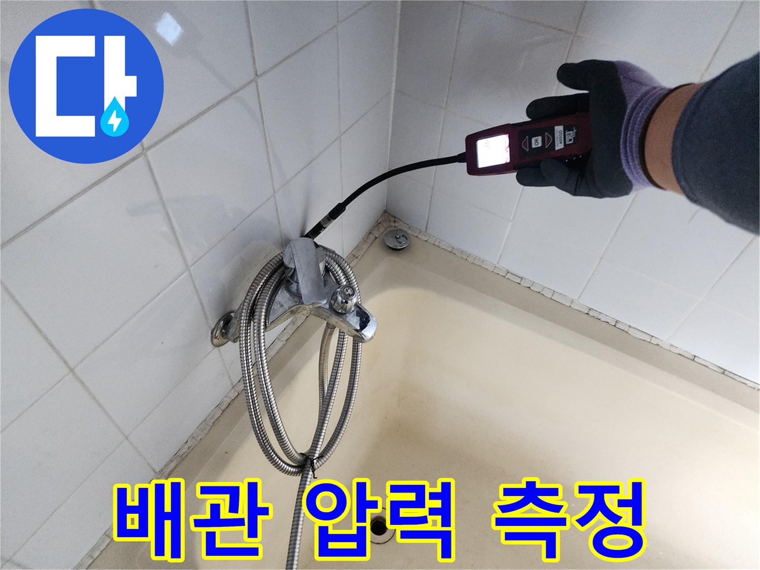 욕실 벽면 타일 사이-배관의 누출 지점을-찾기 위해-장비를 운용하는 모습