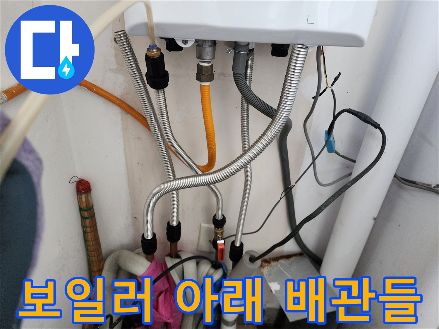 보일러-하부에-연결된-은색-금속-호스와-노란색-배관