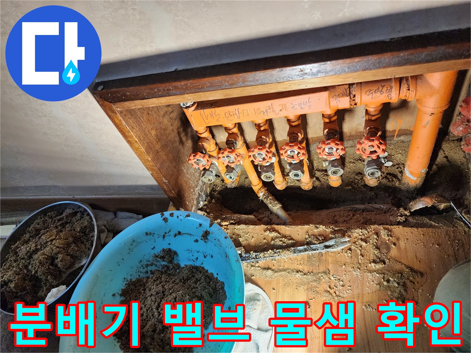오렌지색 보온재가 씌워진 분배기와 젖은 흙이 보이는 작업 현장