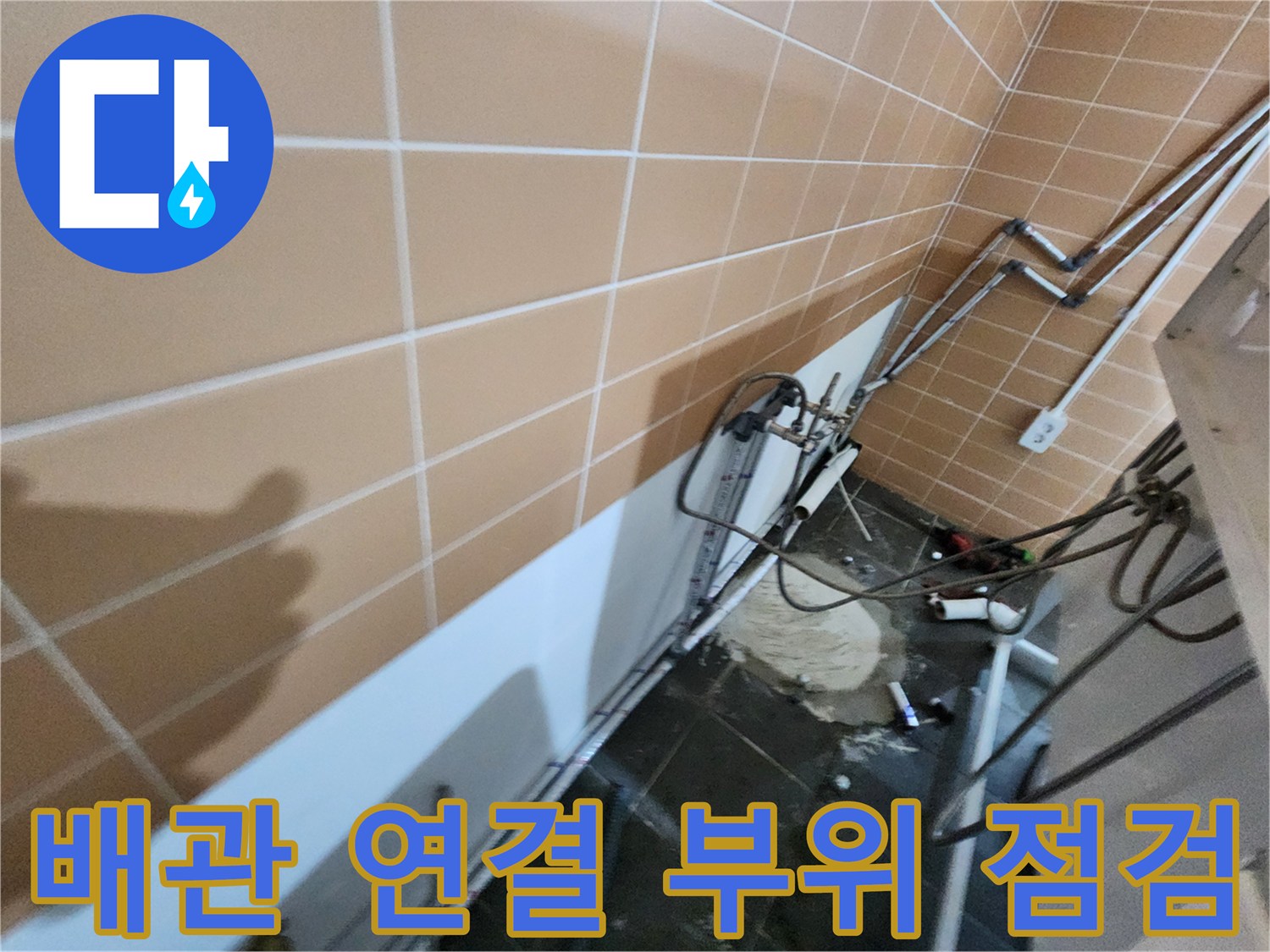 타일 벽면에 설치된 하수 배관들의 결합 상태 확인 중