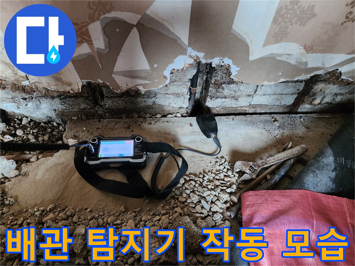 벽면 하단 굴착 부위에서 전문 가스 탐지기를 사용하여 누수 지점을 확인하는 장면입니다.
