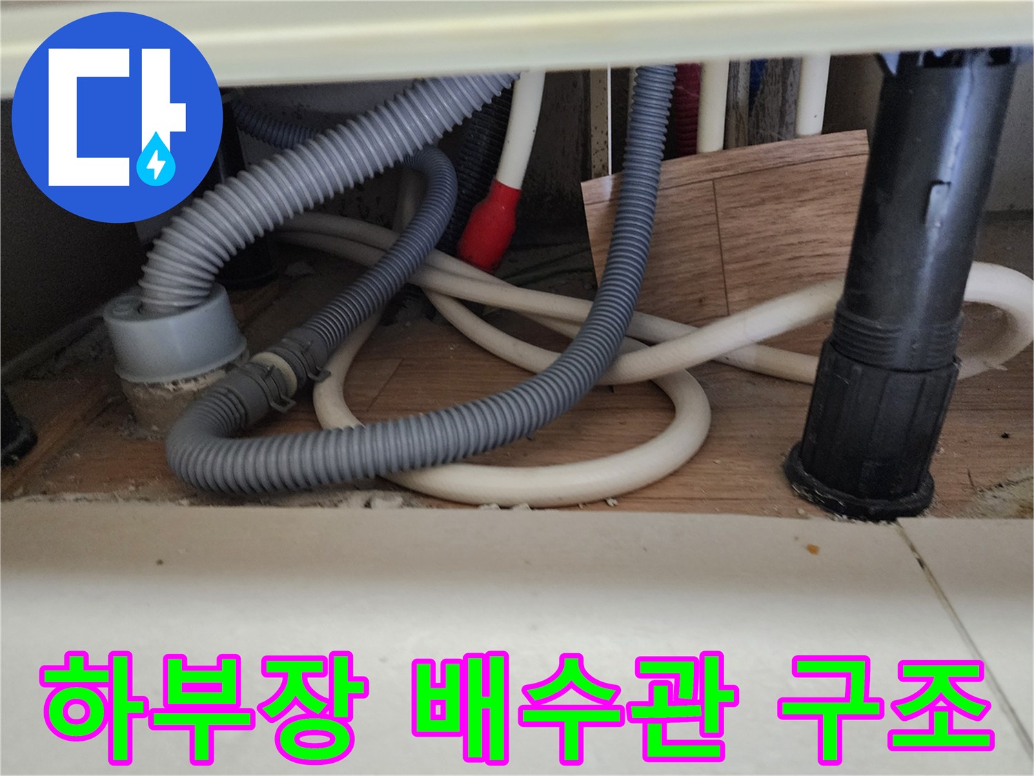 싱크대 하부의 회색 주름 호스와 검은색 수직 배수관 모습