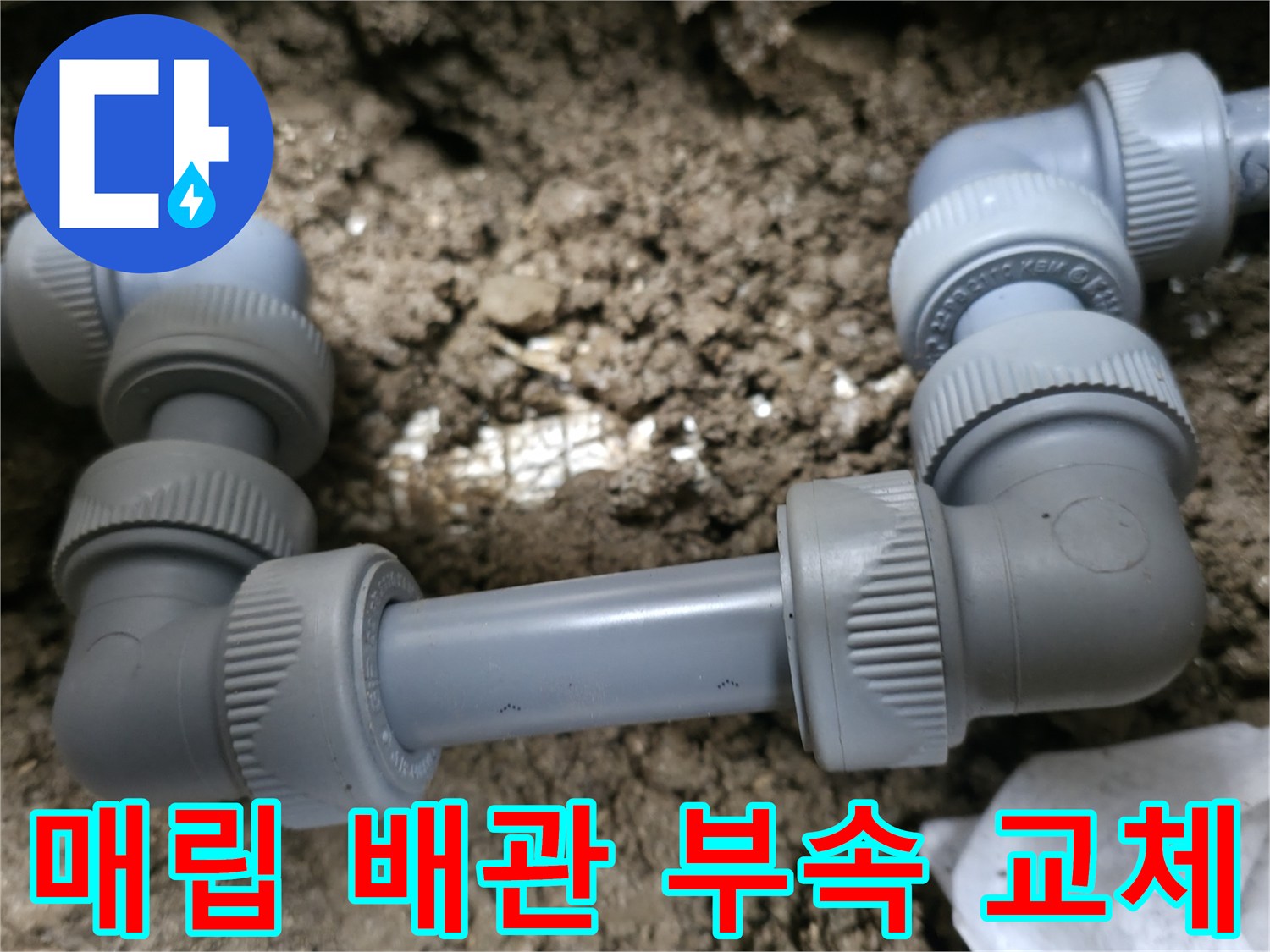 지면 아래에 위치한-회색 배관의 연결 부위와 흙이 섞인 현장 모습입니다.