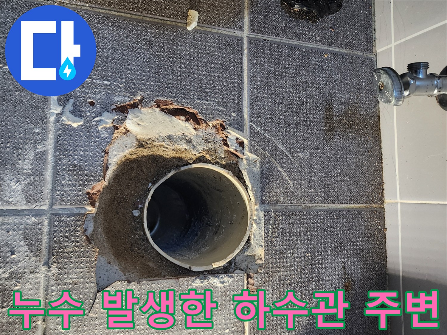 하수관 주위의 젖은 타일과 깨진 마감재를 보여줍니다.