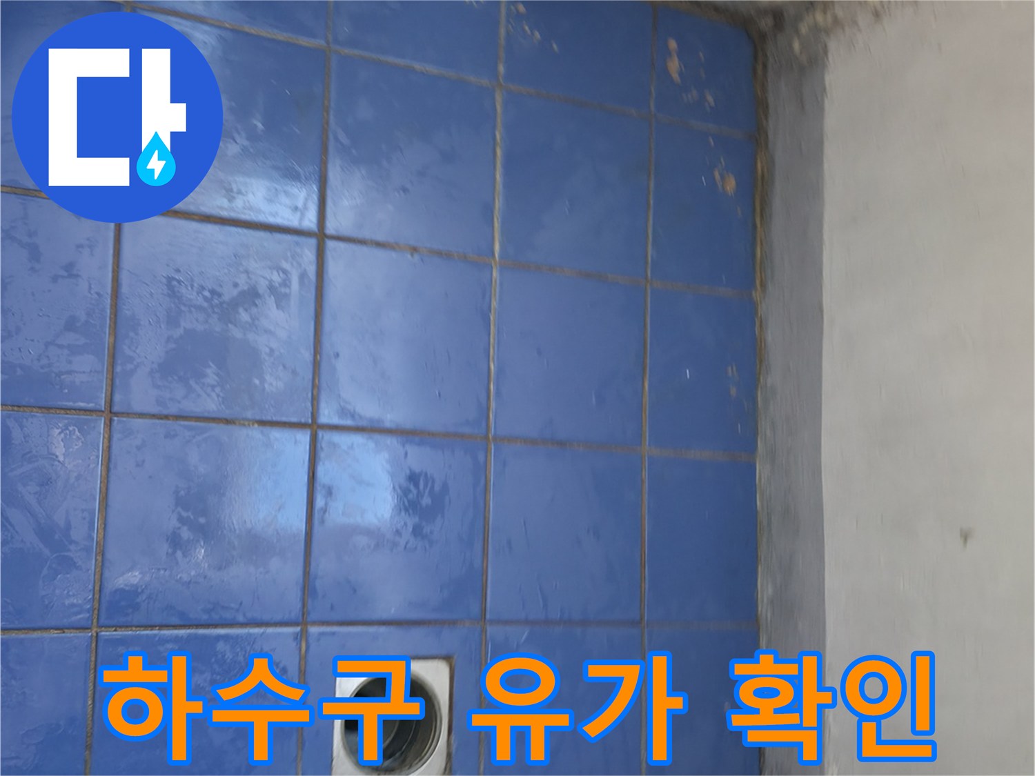 세탁실 하수구 배관 입구와 파란색 타일 바닥 사진입니다.