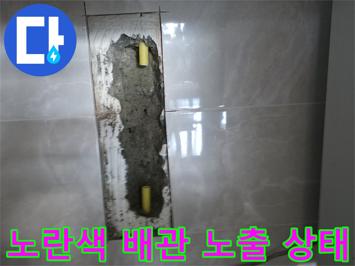 벽면 타일 아래에 드러난 손상된 노란색 배관