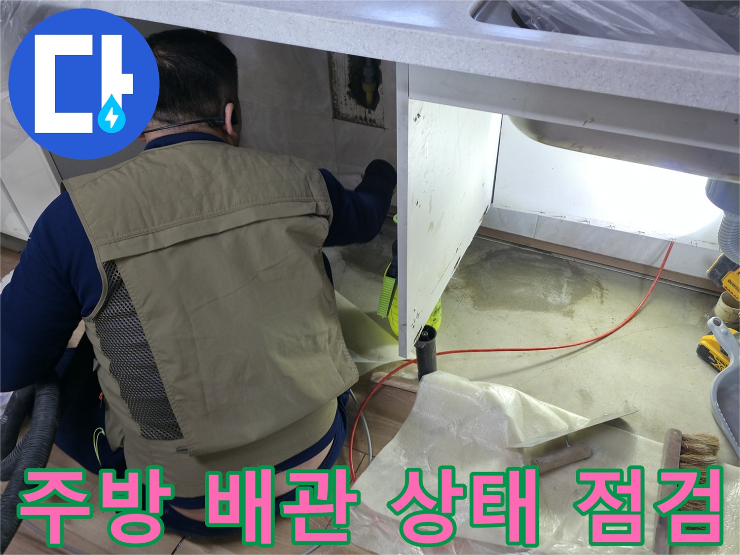 싱크대 아래쪽 공간에서 수도 배관을 면밀히 검사하는 모습입니다.