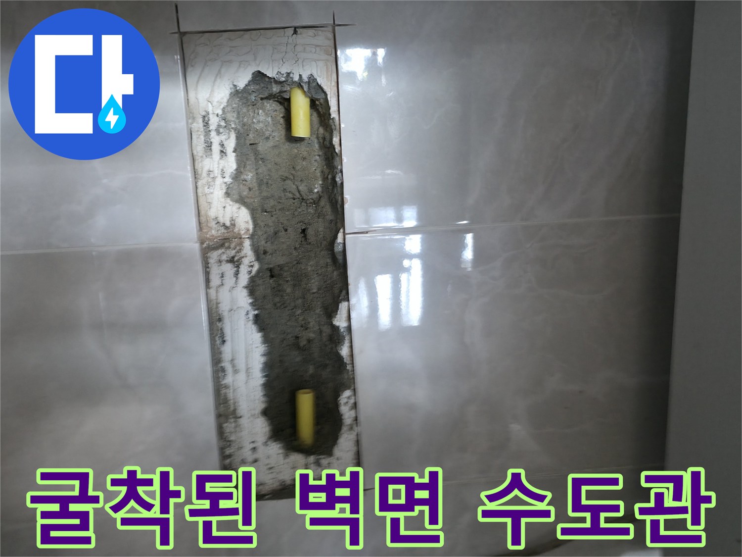 타일 아래 노출된 노란색 수도 배관의 파손 상태