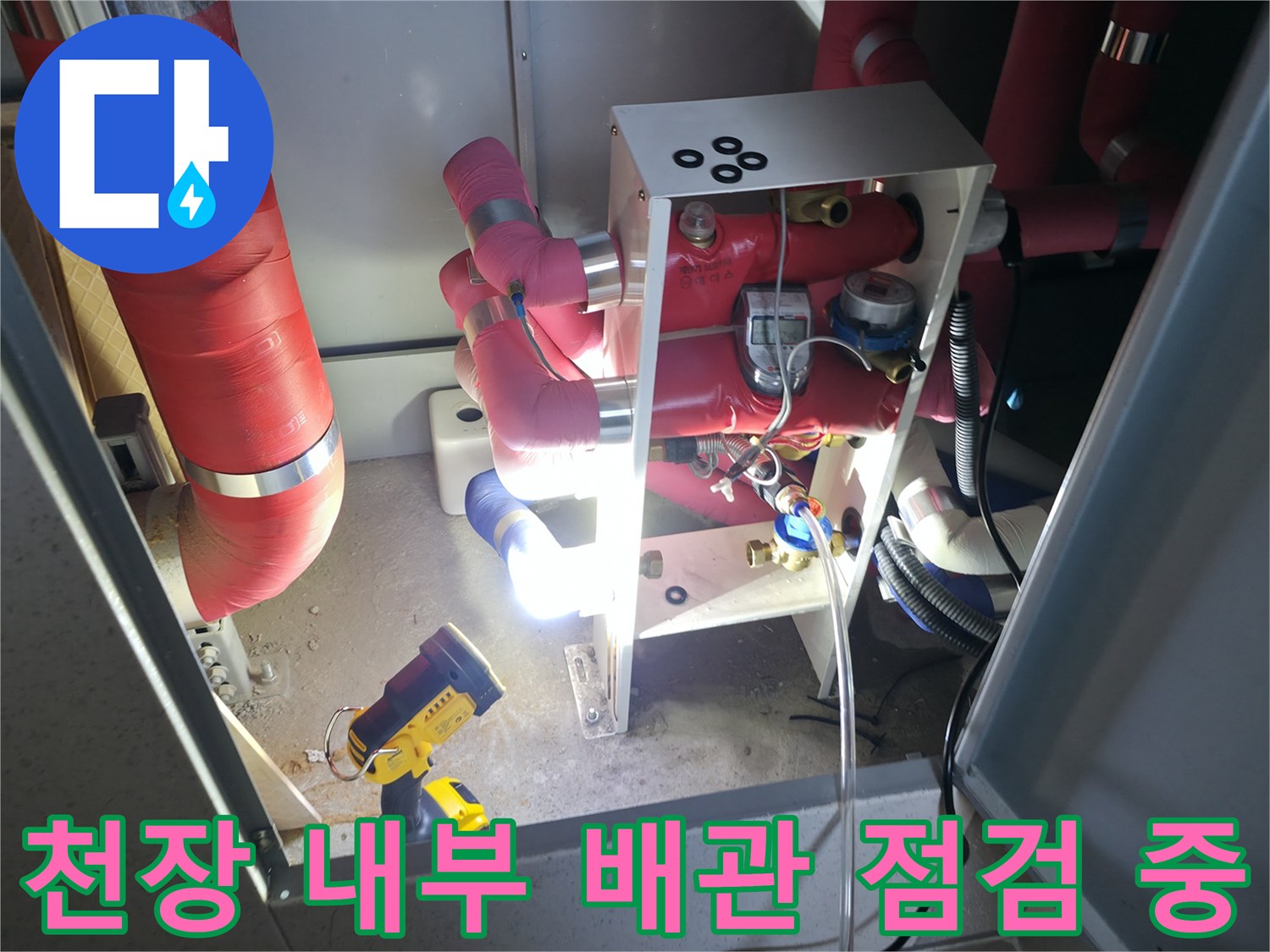 붉은색 관로와 조명 기구가 함께 보이는 천장 내부 작업 모습입니다.
