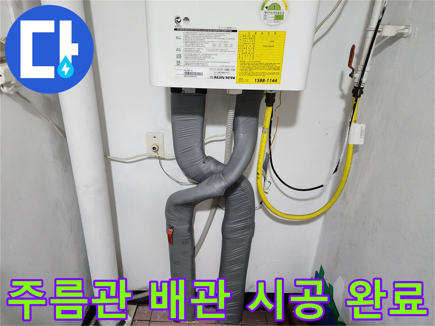 회색 주름관으로 마감된 보일러 하단 배관 연결부