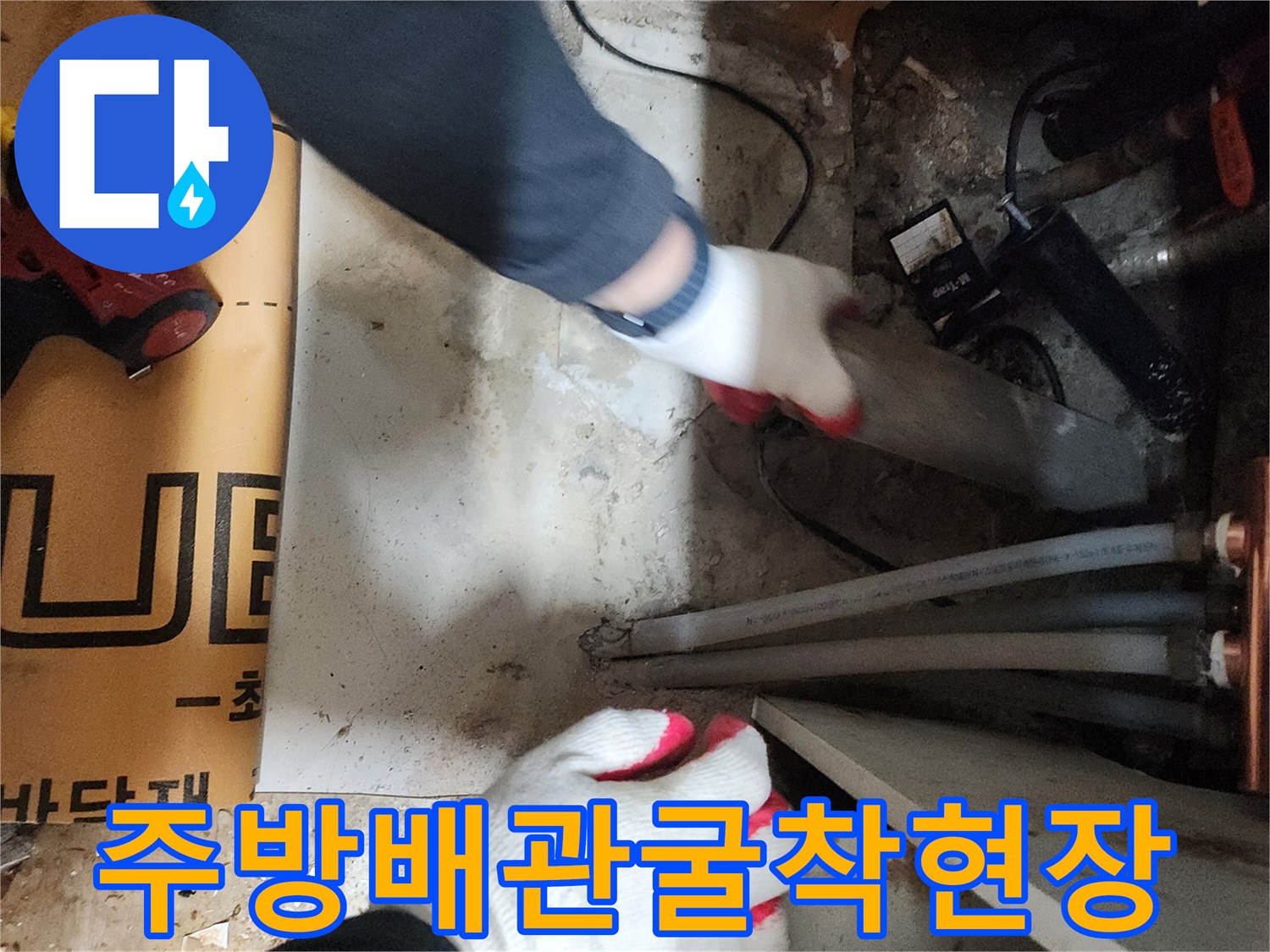 싱크대 밑 배관 주변의 굴착된 바닥과 작업 도구